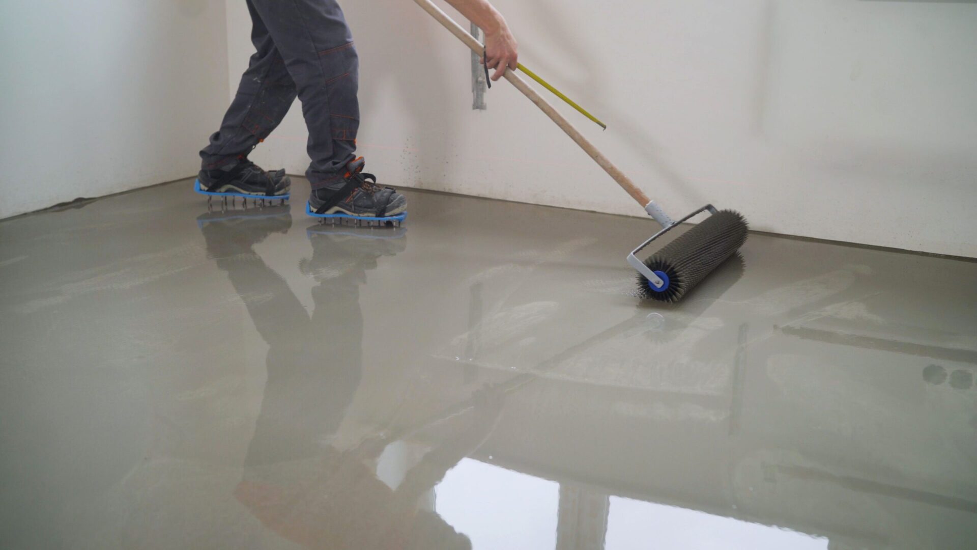 Handwerker trägt Bodenbeschichtung mit Rolle auf