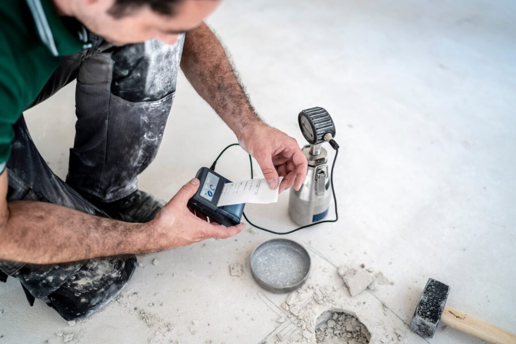 Handwerker führt CM-Messung am Estrich durch